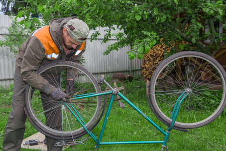 A man is repairing an old bicycle.の写真素材