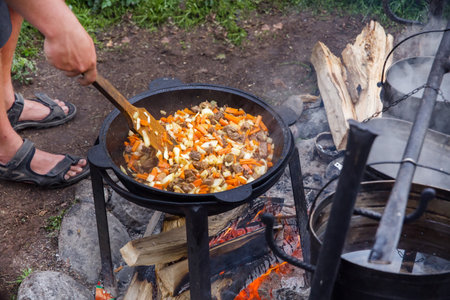 meat and vegetables are cooked in a cauldron outdoors.の写真素材