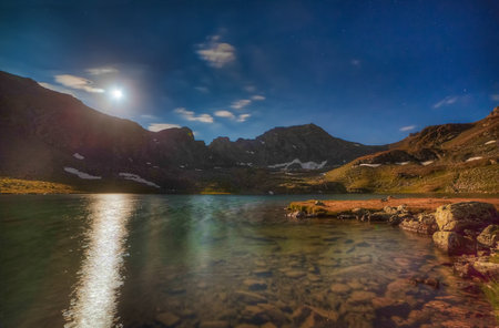 The moon shines over a high lake. Moon path on the water. Night photo. Soft stretch.の写真素材