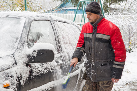 A European man clears snow from a car.の写真素材