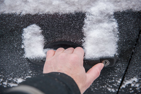 A hand tries to open a frozen car doorの写真素材