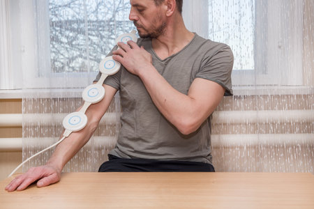 A 49 year old European man is treating his hand with electromagnetic therapy.