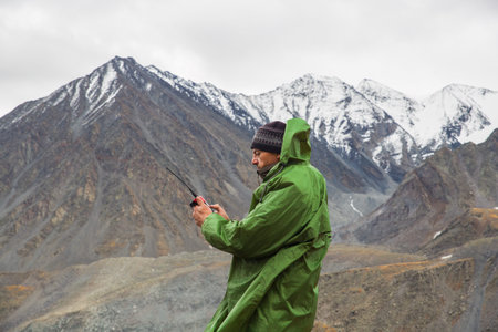 A man in a mountainous area is talking on a walkie-talkie. Tourists using radio communication in the...