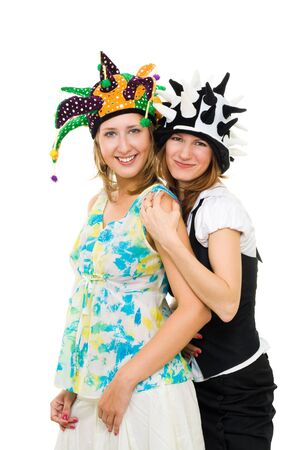 Two young women actors standing together in party hats looking at camera isolated on whiteの写真素材