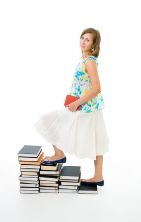 Woman climbing on stairs of knowledge made of books pile with book stanidng in profileの写真素材