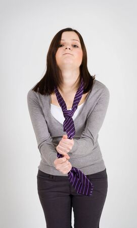 Young tired woman holding tie and woking hardの写真素材