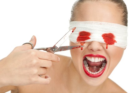 Screaming blind terrified woman with blood and bandage on her eyes and sharp scissorsの写真素材