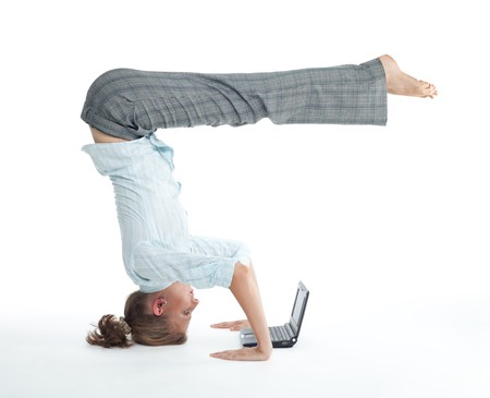 Attractive woman browsing on laptop in unusual yoga pose heels over headの写真素材