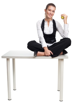 Happy business woman sit on a table and hold appleの写真素材