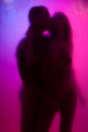 Yong couple have love with color night lights behind the curtainの写真素材