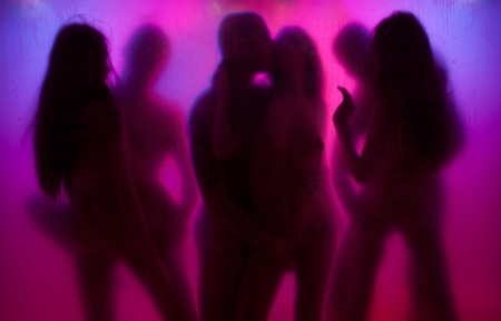 Yong couple having love in night lights with color background behind the curtainの写真素材