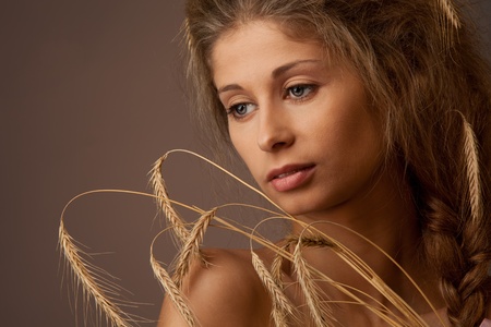 Classic style woman portrait with ears of wheat and calm expression on face with professional make up and hair styleの写真素材