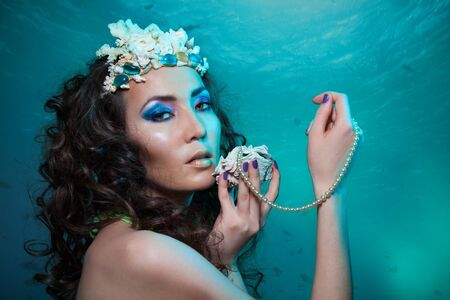 Beauty shoot of a woman holding seashell and pearls necklaceの写真素材