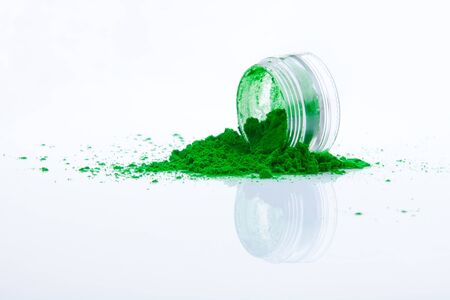 spilled green makeup powder from jarの写真素材