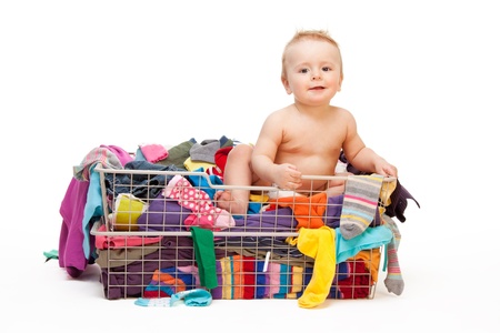 Happy baby in basket with clothes isolated on whiteの写真素材
