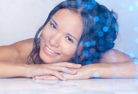 Wellbeing beauty portrait of Asian woman smiling laying on her hands with wet hairsの写真素材