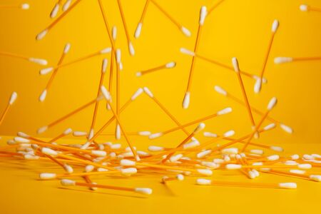 many yellow cotton sticks falling from above on yellow backgroundの写真素材