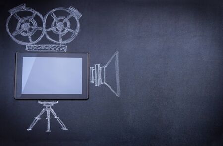 Tablet computer as movie camera on the blackboard with tripod and strobe drawn with chalkの写真素材
