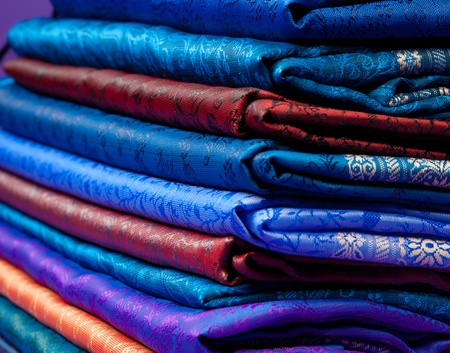 Beautiful silk of different colors and ornament Indian fabric laying in pileの写真素材