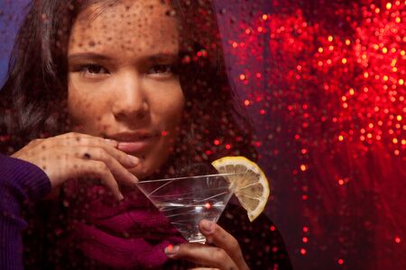 Attractive Asian woman with drink in cold rainy weather behind the glassの写真素材