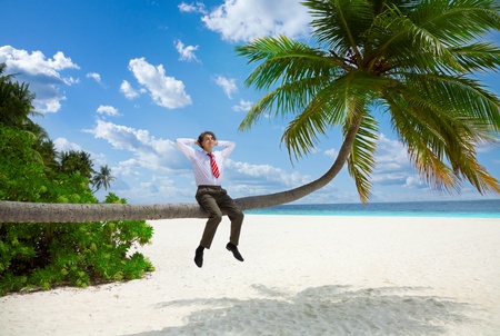 Happy businessman in formal clothes and tie sitting on the palm and relaxの写真素材