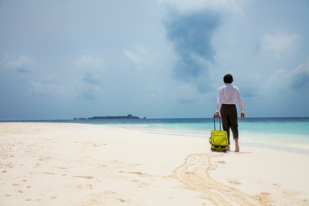 business man with suitcase walking on the beachの写真素材