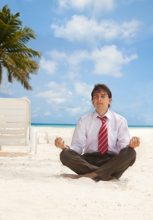 Office worker sitting on the beach an meditatingの写真素材
