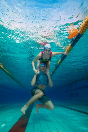 Girl sitting on the boys shoulders - underwater shoot in the poolの写真素材