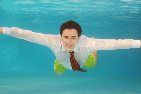 Business man swimming underwater in the pool wearing white shirt and red tieの写真素材