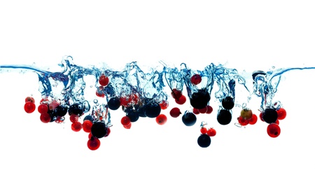 Lot's of currants red and white berries falling into water isolate on whiteの写真素材