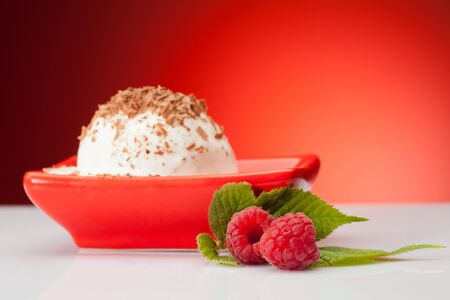 raspberries with vanilla ice cream on red backgroundの写真素材
