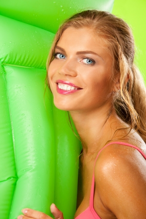 close portrait of happy blonde girl with green inflatable mattressの写真素材