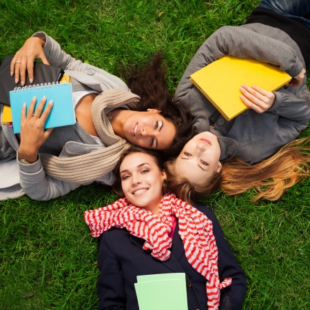 three hot college girls laying on green grassの写真素材