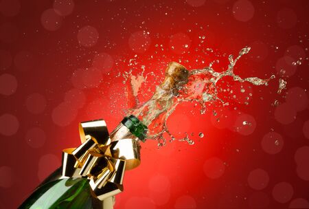 Popping cork from Champaign bottle with lot's of splashes red backgroundの写真素材