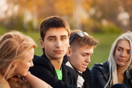 four friends sitting on grass after classes in college parkの写真素材