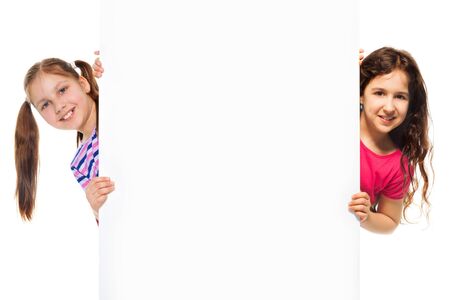 Two beautiful girls showing blank white poster for advertising to be inserted, isolated on whiteの写真素材