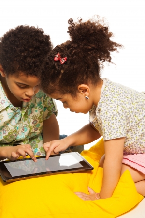 Black boy and girl playing with digital tablet computer and looks very busyの写真素材