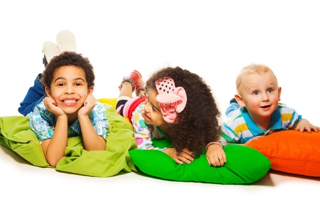 Three happy kids laying on the pillows with big happy smileの写真素材