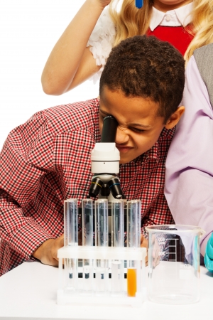 School chemistry research - black eight years old boy looking to microscopeの写真素材