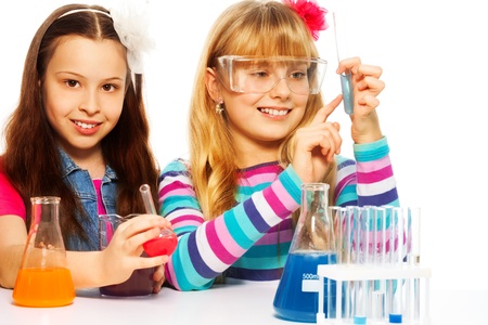 Two girls in chemistry lab class with test tubes and flasks conducting experiments, isolated on whiteの写真素材