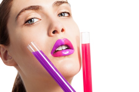 Beautiful woman holding two test tubes with different color liquid as well as her lipsの写真素材