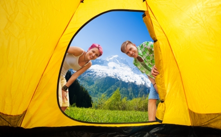 Young man and man looking in the tent with smile on their face and mountains on backgroundの写真素材