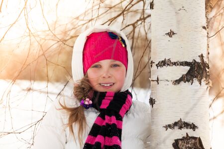 Close portrait happy cute little girl in birch forest at winterの写真素材