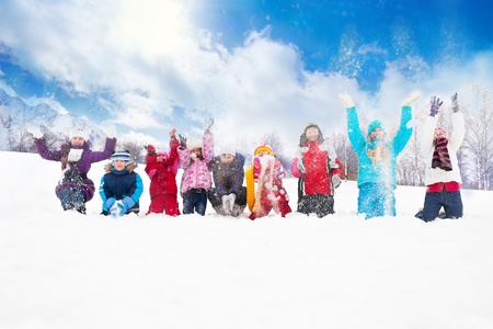 Large group of diversity looking kids boys and girls throwing snow in the air together sitting in a rowの写真素材
