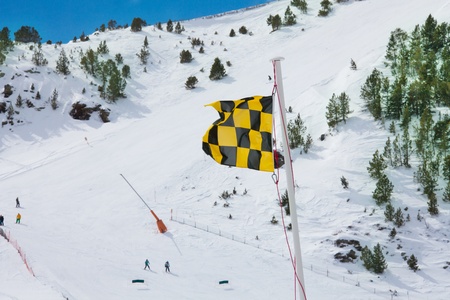 Avalanche warning flag with ski slope and piste on backgroundの写真素材