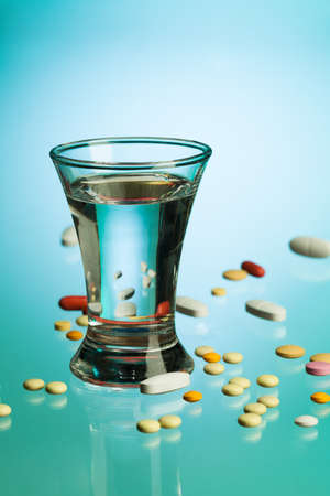 Glass of water for drinking after taking pills and tablets, on blue tableの写真素材
