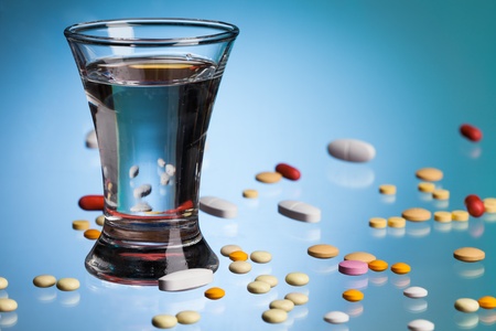 Glass of water for drinking, drugs, tablets and pills, on blue tableの写真素材