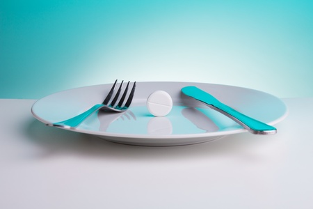 Medicine for digestion concept with plate with big white tablet and for and table knifeの写真素材
