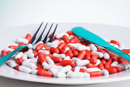 Medicine for digestion concept with plate with many white and red tablets and for and table knifeの写真素材
