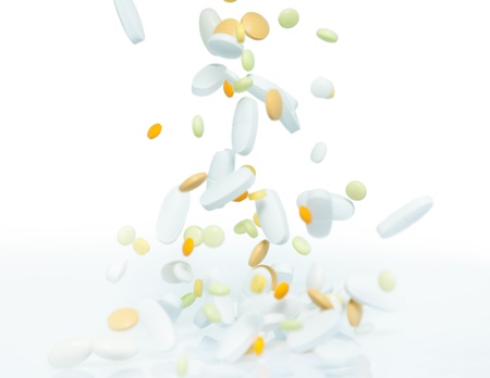 Large amount of different drugs, pills and tablets falling on the table, isolated on white